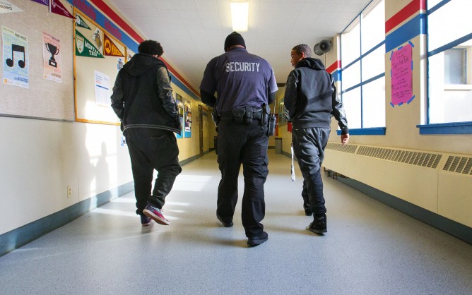 School security escorting student through hallways