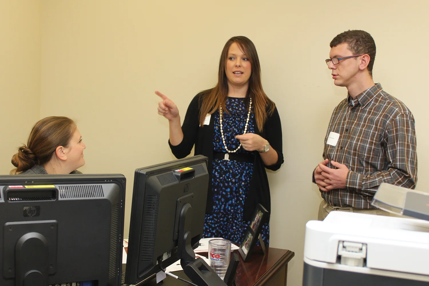 A student stands with two job shadow staff members in an office