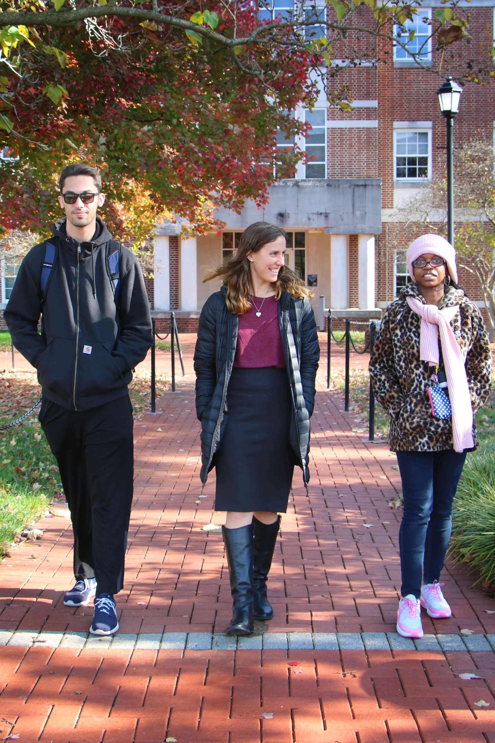 Two students walk on a brick pathway with Rebecca Jewell