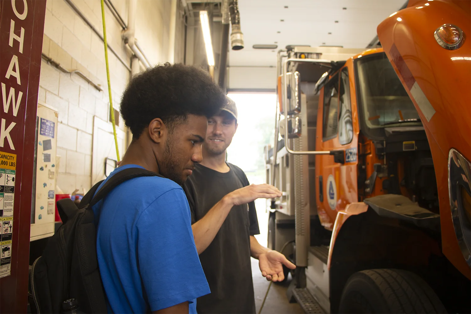 A CLSC student with a DelDOT manager in a garage by a dump truck