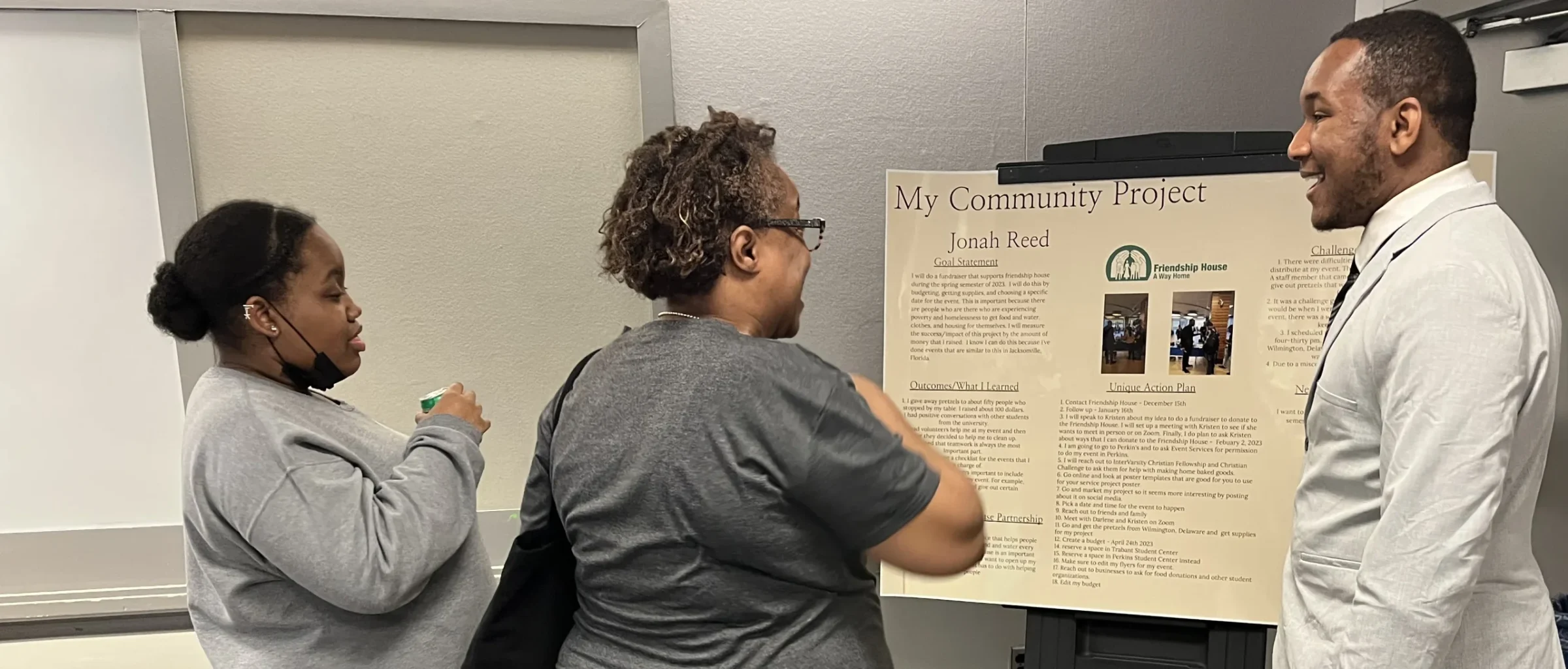 A student presents their community project poster to two visitors