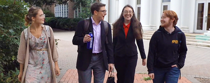 Students walk with a mentor on college campus.