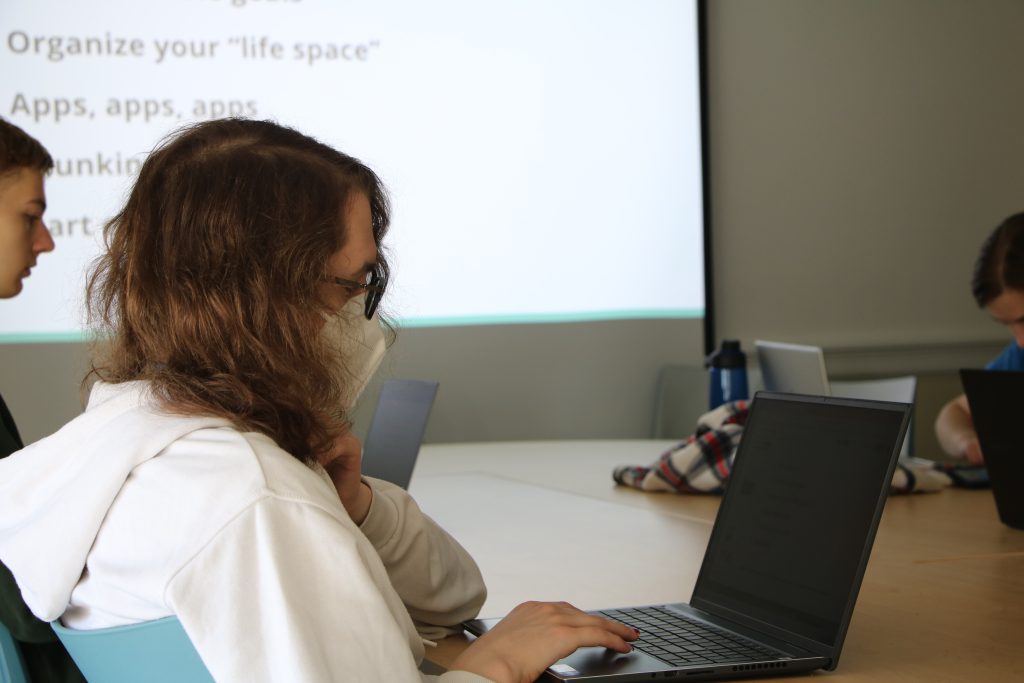 A student follows a presentation on their laptop during a group coaching session