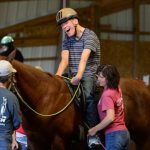 Young man rides horse during therapeutic horseback riding session