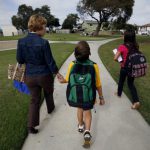 A mother walks her two children to school