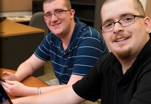 iCanConnect.  Image of two people sitting at a desk using mobile devices.