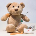 A teddy bear with a needle used to illustrate immunizations to children