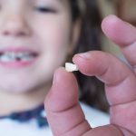 Child holding front tooth that fell out