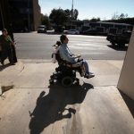 Man utilizes wheelchair on sunny sidewalk