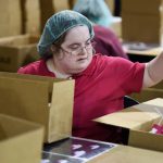 A woman repackages plastic sprayers at a sheltered workshop for adults with disabilities.