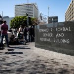 Journalists wait outside the Edward R. Roybal Center and Federal Building in Los Angeles