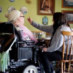 A caregiver assists a woman with a disability.