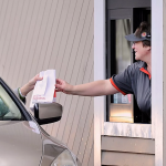 A Burger King employee serves a customer through the restaurant’s drive-through window