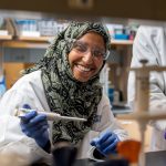UD doctoral student Salma Al Saai in a lab conducting research with a dropper and a flask
