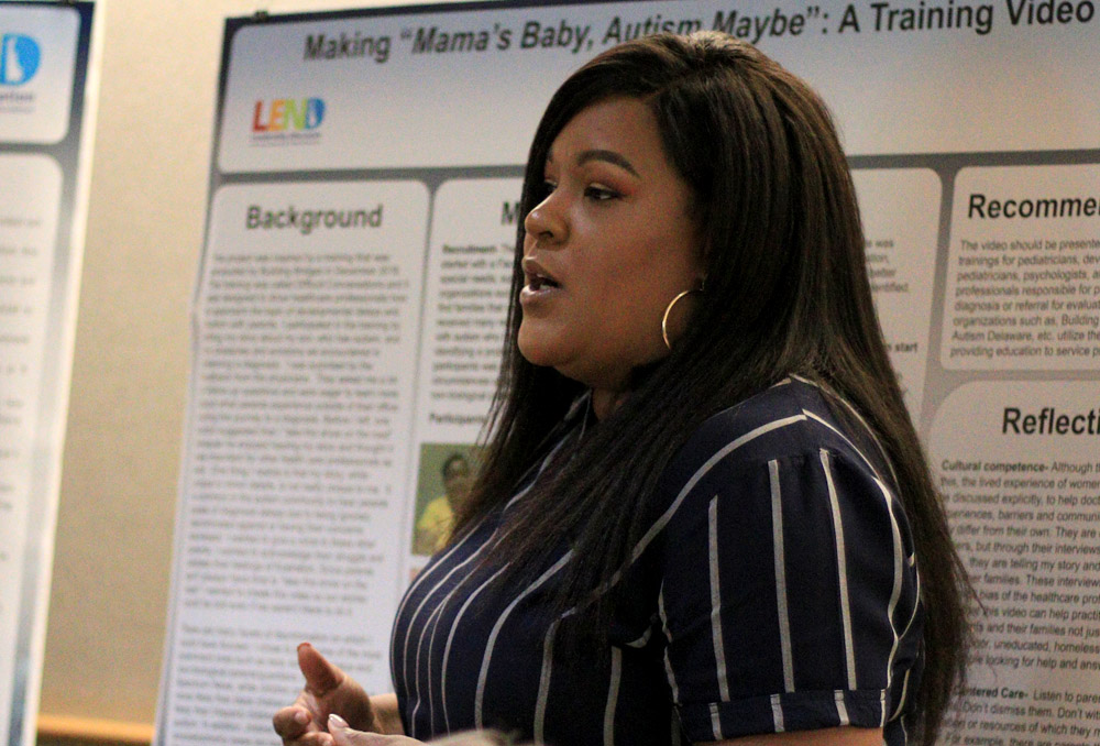 LEND trainee Kendra Haynes stands before her poster she designed while delivering a presentation to fellow graduates and advisers