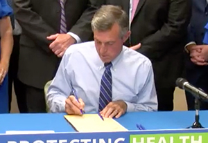 The coverage of oral health.  Image of governor Carney signing a bill.