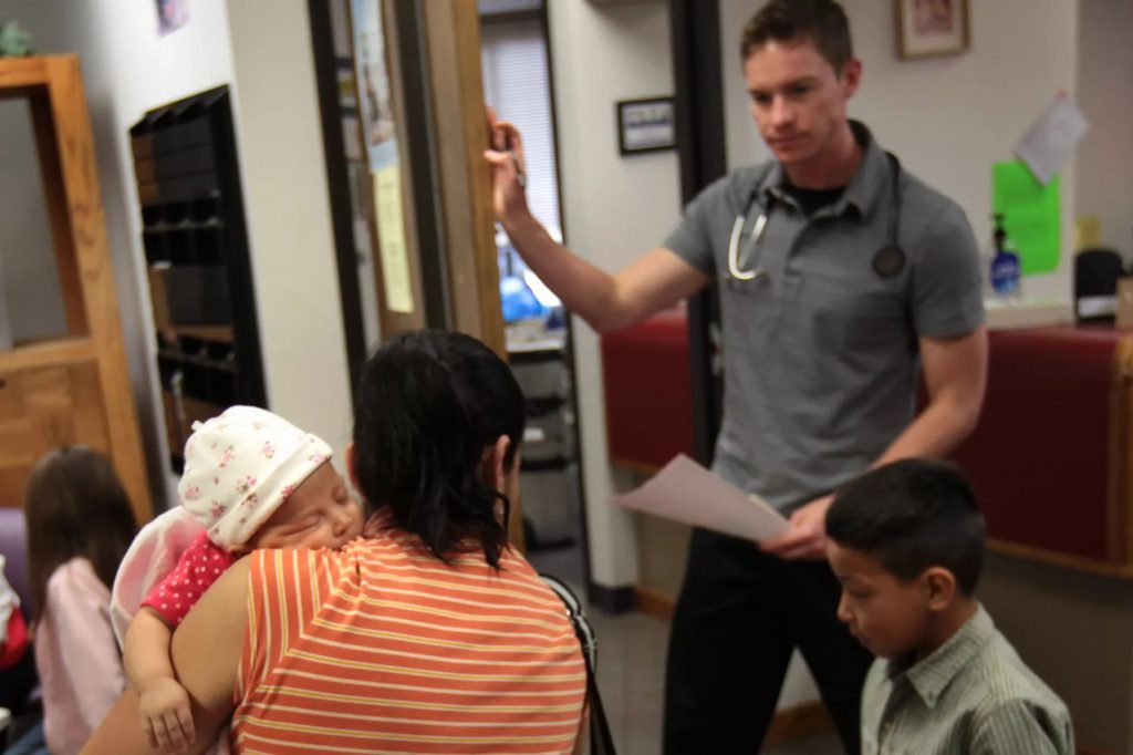An uninsured woman takes her children in for a medical check-up at a low-cost clinic