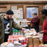 Customer looks at items in a Chicago food pantry while a worker lends assistance