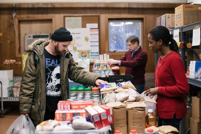 Customer looks at items in a Chicago food pantry while a worker lends assistance