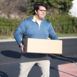 Senator Anthony Delcollo carries a box of food into the Absolam Jones Community Center.