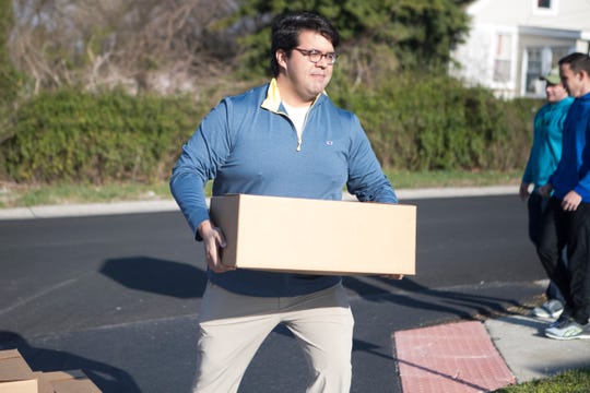 Senator Anthony Delcollo carries a box of food into the Absolam Jones Community Center.
