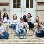 UD chapter of Canine Companions for Independence pose with several service animals on the steps of a school building