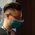 A nurse wears a protective mask while treating patients