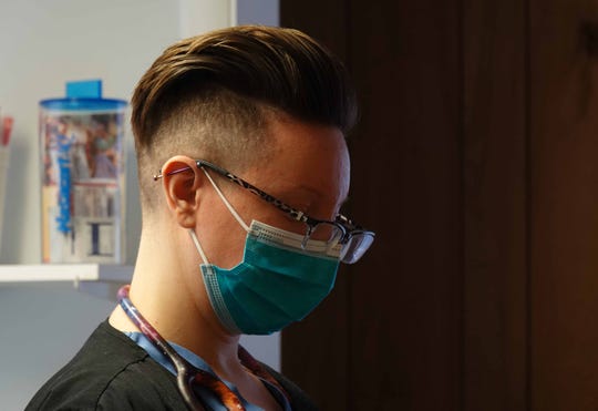 A nurse wears a protective mask while treating patients