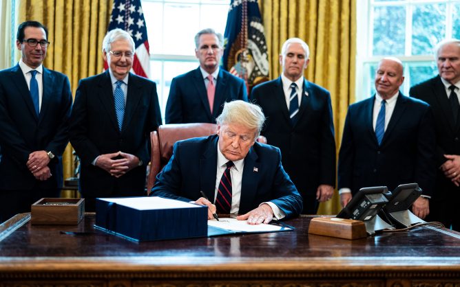President Donald Trump signs the CARES Act in the oval office