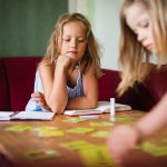 a pair of twin girls playing a game at a table