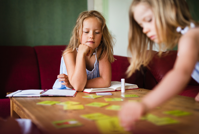 a pair of twin girls playing a game at a table