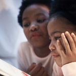 a mother supervising her child reading of a book