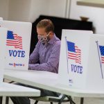 Man in mask casting his ballot