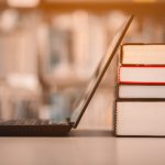 open laptop and reference books stacked in a library study environment