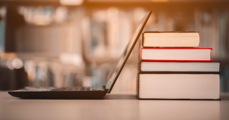open laptop and reference books stacked in a library study environment