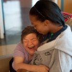 A resident and worker embrace at a intermediate care facility