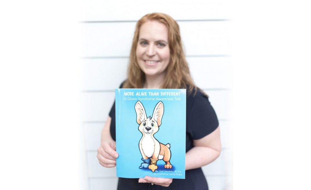 Gail Hamblin stands with her children’s book “More Alike Than Different.”