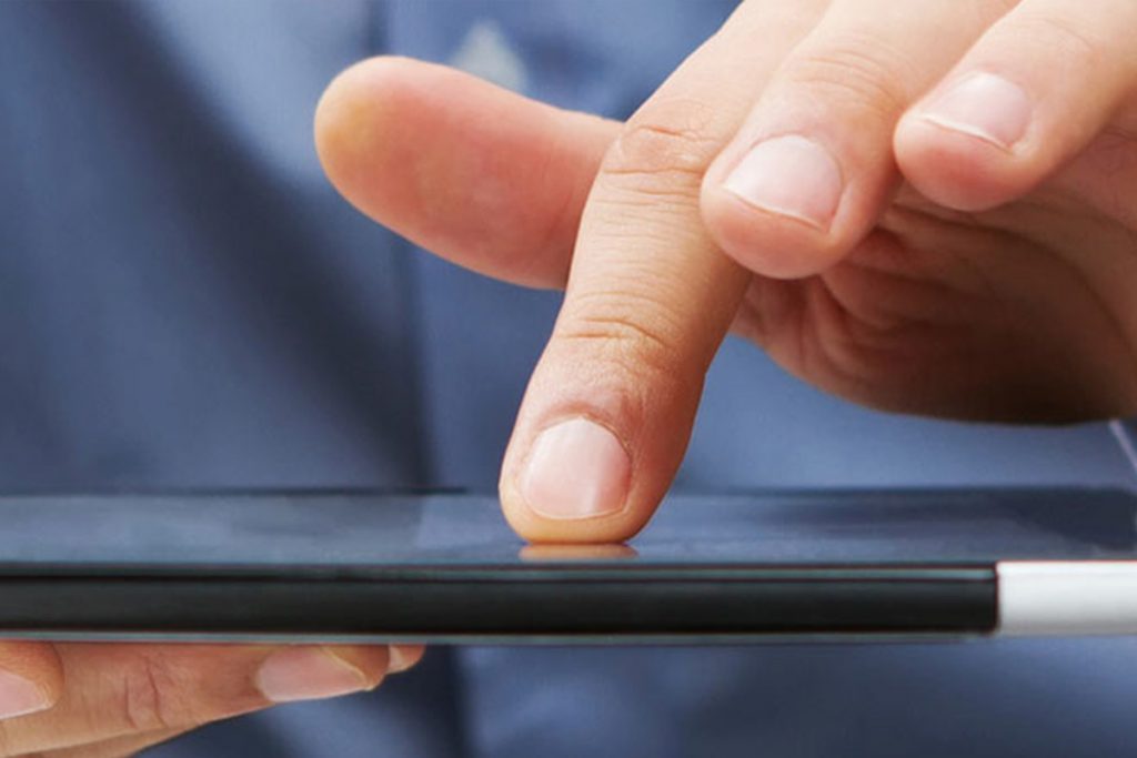 finger touching tablet device surface while cradled in other hand