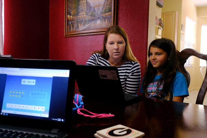 A mom and her daughter go over school lessons using a laptop computer