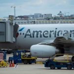 An airplane marked American sits on the runway being checked before its next flight