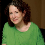 The playwright, novelist and activist Susan Nussbaum in an undated photo. She has curly, shoulder-length brown hair and wears an oversized green t-shirt.
