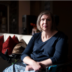 Julie Jennings sits in a powered wheelchair. Strong lighting falls on her from the left. Her right side is in shadow.