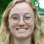 Jayla Godfrey has wavy blond hair and wears round, wire-framed glasses.