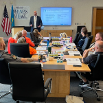 Chuck Sawchenko leads a training session for first responders. Attendees sit around a conference table.