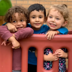 A diverse group of three small children on playground equipment
