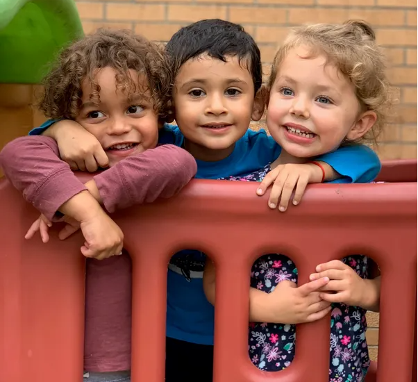 A diverse group of three small children on playground equipment