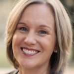Annie Slease has blonde, bobbed hair, light-toned skin and a warm smile