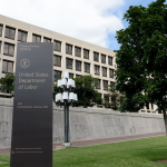 Sign and tree outside of a brutalist government building, the US Department of Labor