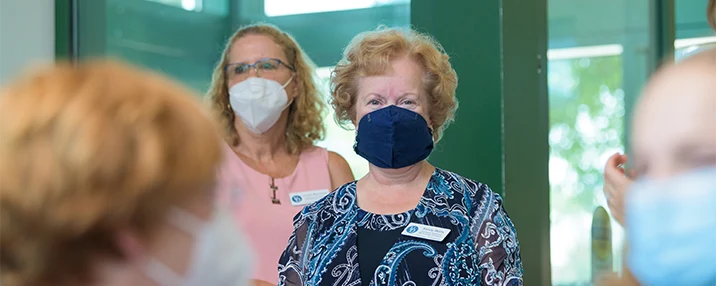 CDS staff at the grand opening of the new Assistive Technology Resource Center in Milford. Two people with masks stand in front of a vestibule of glass and green painted metal.