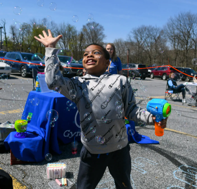 A child with medium-dark-toned skin plays with bubbles.